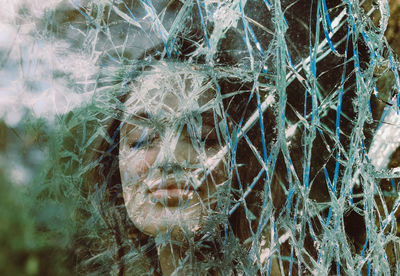 Digital composite image of women with closed eye seen through broken glass