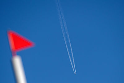 Low angle view of airplane flying against clear blue sky