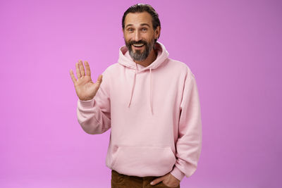 Midsection of man standing against pink background