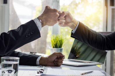 Cropped image of colleagues fist bumping in office