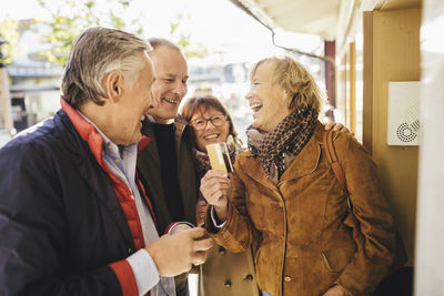 Happy senior woman with friends buying tickets through credit card at musical theater