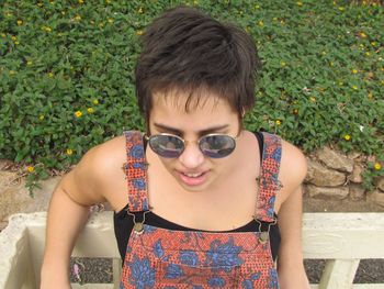 High angle view of young woman wearing sunglasses by railing on field