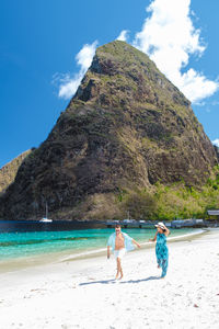 Rear view of woman standing at beach against sky