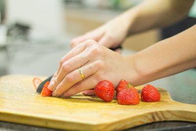 Close-up of hand cutting strawberries on chopping board