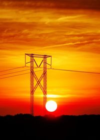 Electricity pylon on silhouette landscape at sunset