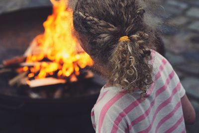 Rear view of girl standing by fire pit at back yard