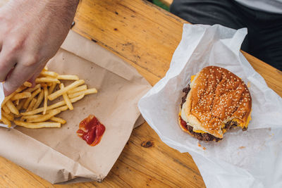 Man eating french fries with ketchup and cheeseburger