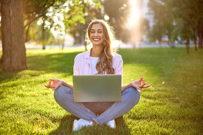 Smiling young woman using mobile phone in park