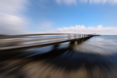 Blurred motion of pier against sky at beach