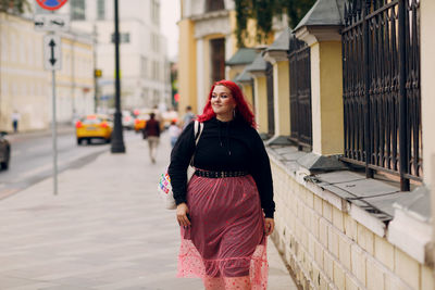 Woman standing on street against building in city