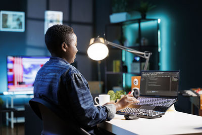 Rear view of man using laptop at office