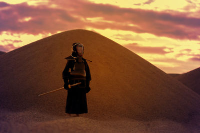 Man standing on desert against sky during sunset