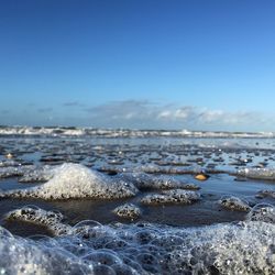 Close-up of surf at sea shore against blue sky