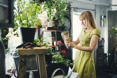 Mid adult woman holding pots in interior design shop