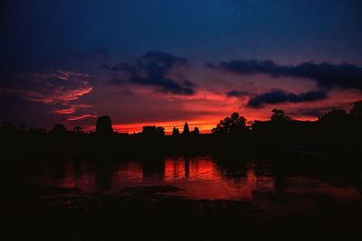 Silhouette trees by lake against sky during sunset