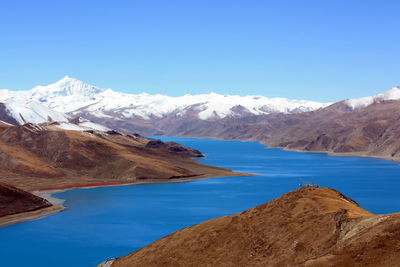 Scenic view of lake and mountains against clear blue sky