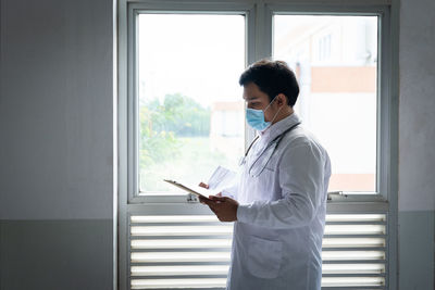 Side view of young man looking through window