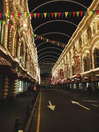 Illuminated road amidst buildings in city at night