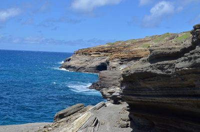 Rock formations on shore against blue sky
