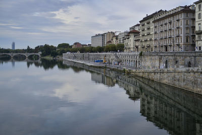 Buildings by river against sky in city