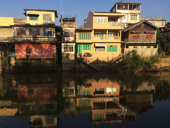 Residential buildings by river against sky