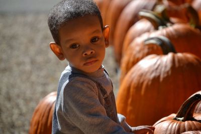 Side view of boy holding pumpkin on field