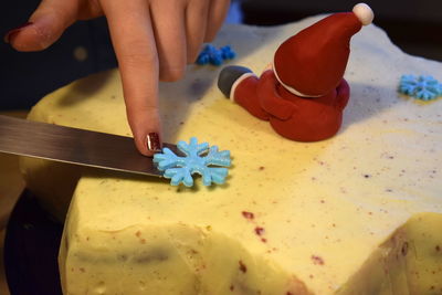 Woman positioning snowflake by santa claus on cake