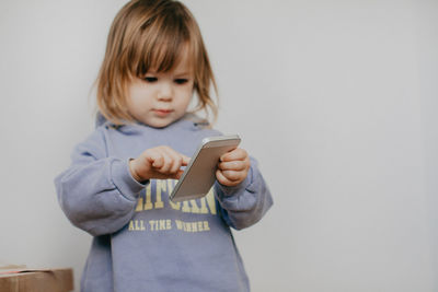 Portrait of cute girl with arms crossed standing against wall