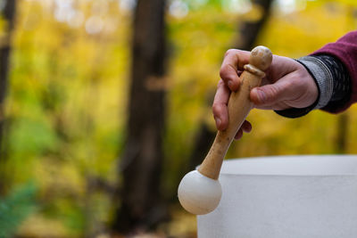 Cropped hand of man holding ringing bowl outdoors