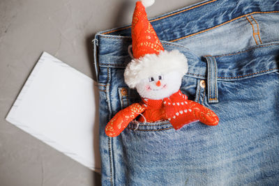Directly above shot of blank photograph with stuffed toy in jeans pocket on gray background