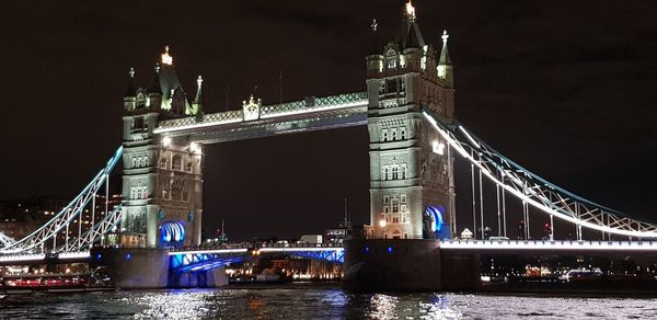 Illuminated bridge over river at night