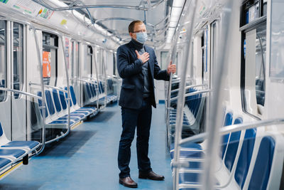 Businessman wearing mask while standing in train