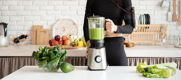 Midsection of woman making drink in kitchen