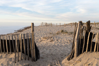 Wooden posts on sand against sky