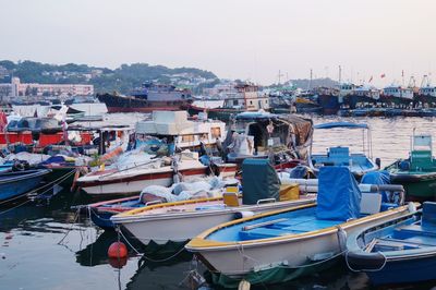 Boats moored at harbor against clear sky