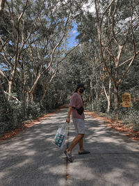 Rear view of woman walking on footpath in forest