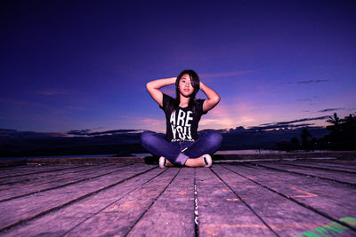 Portrait of woman sitting on wooden pier