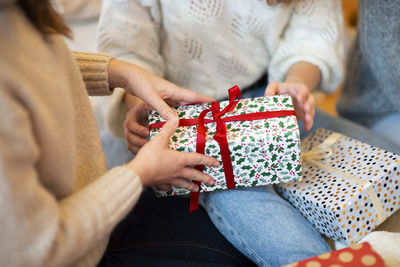 Midsection of woman holding mobile phone while sitting in box