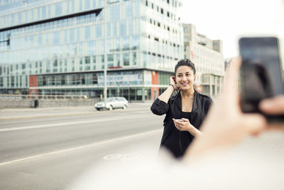 Cropped image of woman photographing female friend in city