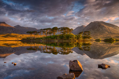 Scenic view of lake and mountains against dramatic sky