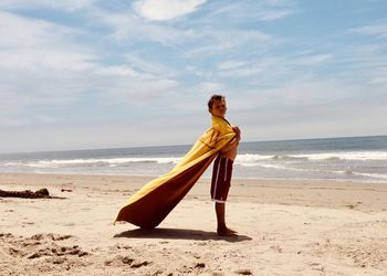 Boy with towel as a cape on beach