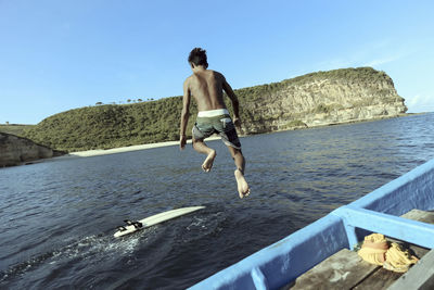 Asian surfer jumping into sea