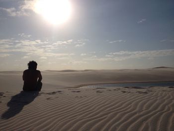 Rear view of man sitting by lagoon at the national park