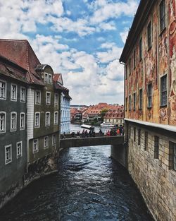 Canal amidst houses against sky in city