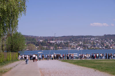 Group of people on street amidst trees against sky