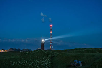 Illuminated tower amidst buildings against sky at night