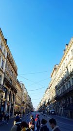 People on city street against blue sky