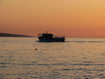 Silhouette boat in sea against sky during sunset