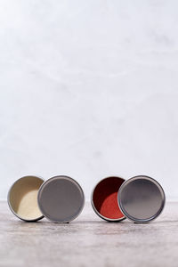Colorful lip balms in round tin cases on light background with shadow overlay, mockup design, label