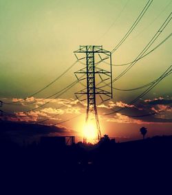 Low angle view of electricity pylon against sky during sunset